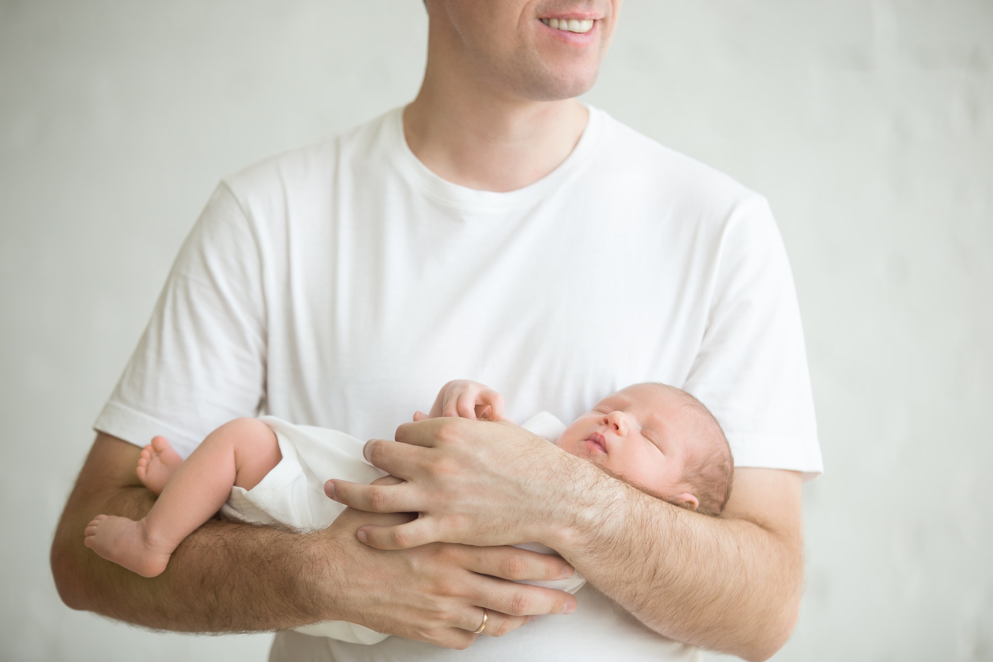 Newborn child sleeping in dads arms